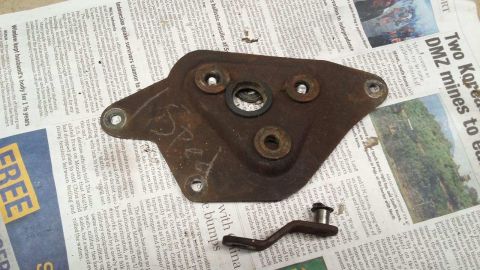 1964 Ford Fairlane - A rusty metal bracket with bolts and a rubber seal is placed on top of a newspaper. The newspaper has headlines about Korean DMZ mines and…