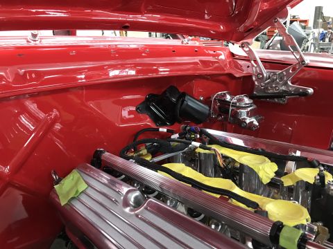 1964 Ford Fairlane - Close-up view of the engine bay of a red classic car, showing chrome components, fuel rails, and wiring harnesses. The master cylinder and…