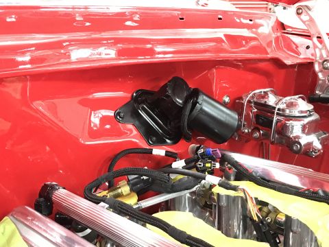 1964 Ford Fairlane - A close-up view of the engine bay of a red classic car, showing a black windshield wiper motor assembly mounted to the firewall, next to a…