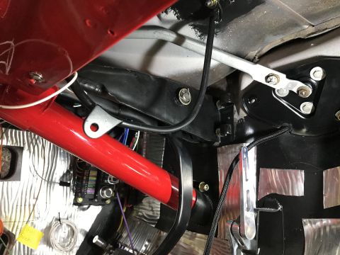 1964 Ford Fairlane - A close-up view of the interior of a vehicle, focusing on the red roll cage, wiring, and a fuse box. Various metal components and sound-dam…