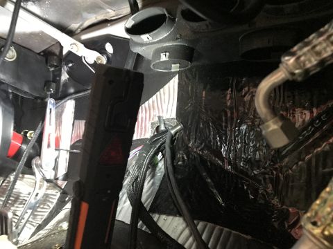 1964 Ford Fairlane - A close-up view of the interior of a vehicle, showing various components of the HVAC system and wiring harnesses. A black flashlight with a…