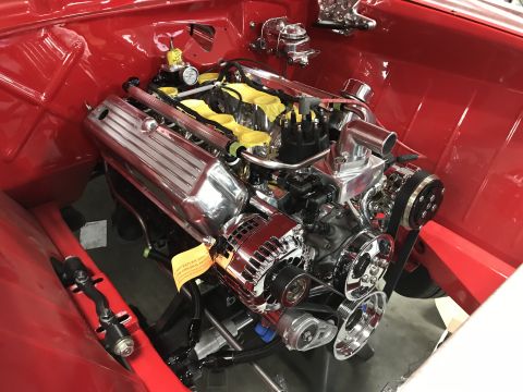 1964 Ford Fairlane - A highly polished chrome engine is installed in the engine bay of a red classic vehicle. The engine features chrome valve covers, intake ma…