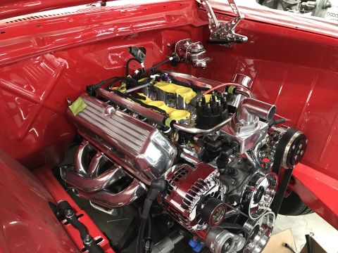 1964 Ford Fairlane - Close-up view of a highly polished chrome engine installed in a red vehicle's engine bay. The engine features chrome valve covers, exhaust…