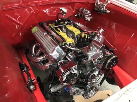 1964 Ford Fairlane - A highly polished chrome engine is installed in the red engine bay of a classic vehicle. The engine features chrome valve covers, exhaust h…