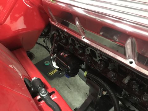 1964 Ford Fairlane - A close-up view of a red vehicle's engine bay, focusing on the engine block and a black component with white text that reads "MASTER FLOW".