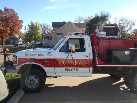 1994 Ford Bronco - A Ford F350 fire truck with "BRUSH 160" and "HOY RURAL FIRE DIST. 3" markings is parked on a sunny day.