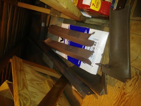 1996 Ford Bronco - Several brown interior trim pieces are piled on top of a cardboard box in what appears to be an attic or storage space.