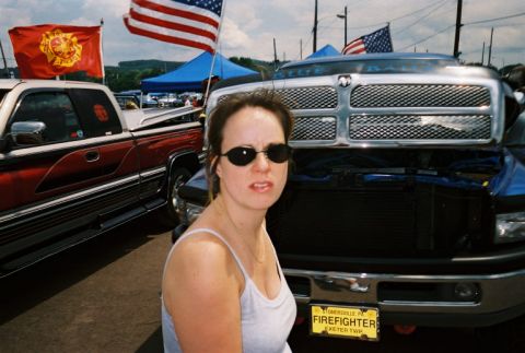 1994 Ford F-150 - A woman poses in front of a Dodge Ram truck at an outdoor event with American flags visible.