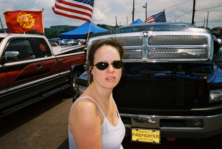 Front view of a blue Dodge Ram truck with a chrome grille and a yellow license plate reading "FIREFIGHTER"