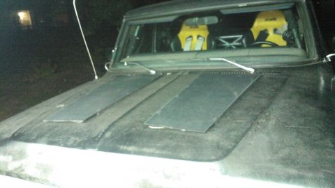 1978 Ford Bronco - The front of a 1978 Ford Bronco shows a dark hood with inset panels and yellow racing seats inside.