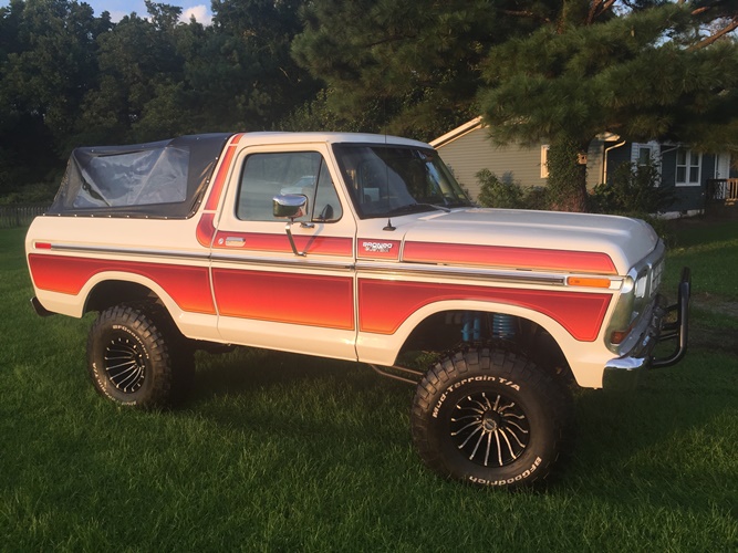 1979 Ford Bronco, white and red striped with soft top, lifted on off-road tires