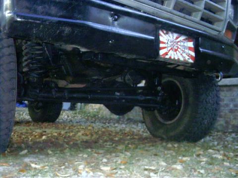 1985 Ford Bronco - Close-up of the front axle and suspension of a 1985 Ford Bronco, a custom decal on the bumper.