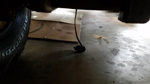 1994 Ford Bronco - A close-up view of the undercarriage of a vehicle, with a tire and a loose wire visible.