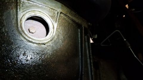 1994 Ford Bronco - Close-up of a greasy transmission housing with a visible bolt.