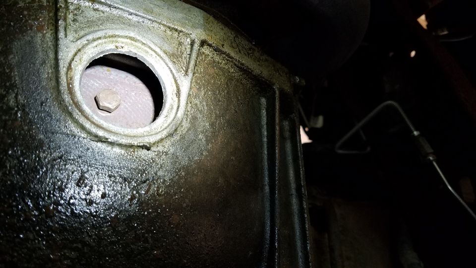 Transmission housing with a hex bolt in a circular opening, covered in grease