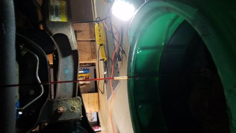 1994 Ford Bronco - Close-up view of a green fender and suspension components, illuminated by a work light.