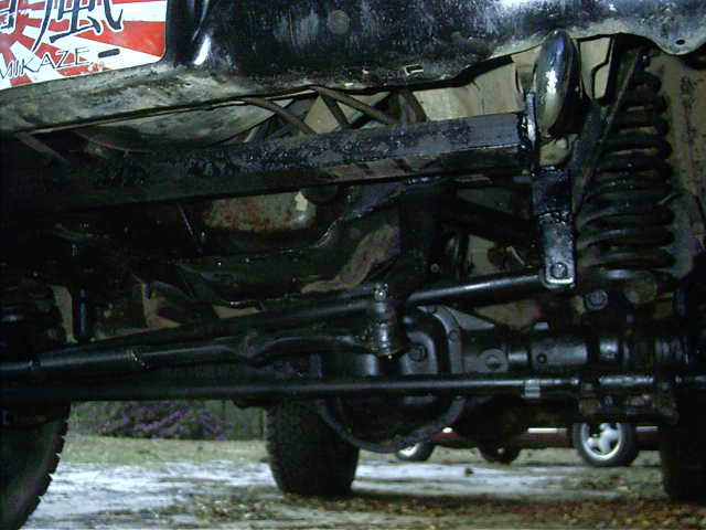 Under-truck view of lifted 4x4 front axle, coil spring, radius arm and steering linkage
