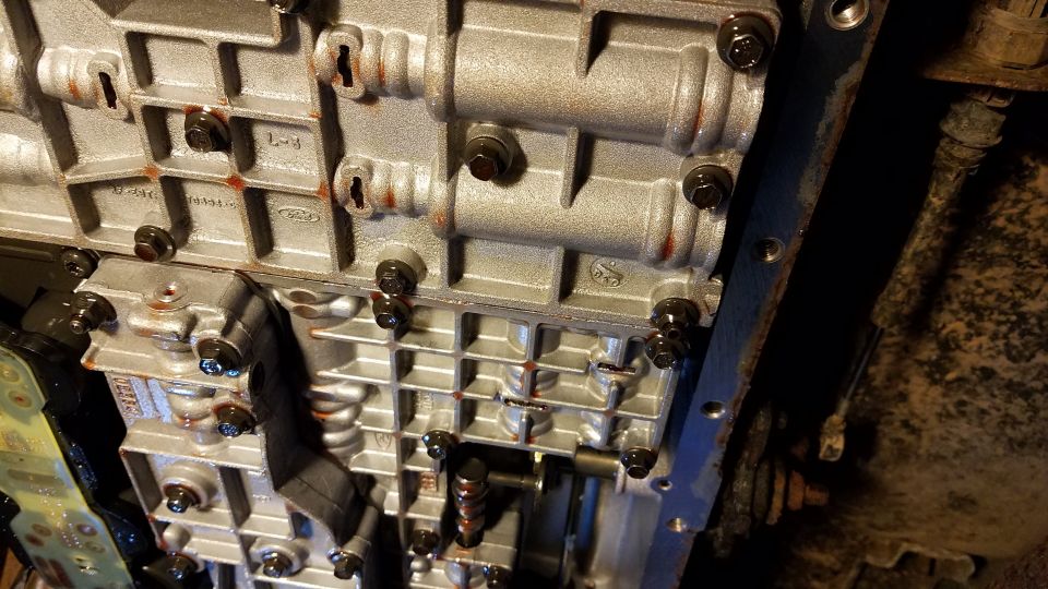 Close-up of an automatic transmission valve body with visible bolts and internal components