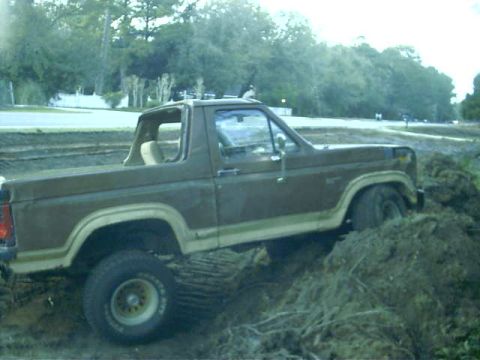 1985 Ford Bronco - This 1985 Ford Bronco appears to be stuck in a muddy, dirt-filled area, viewed from its 3/4 front side.