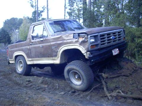1985 Ford Bronco - Brown 1985 Ford Bronco navigating off-road conditions.