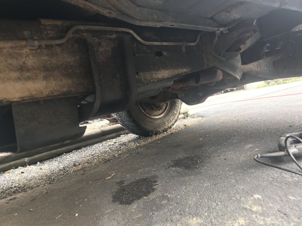 Underside of a vehicle showing frame, exhaust, tire, and underbody protection.
