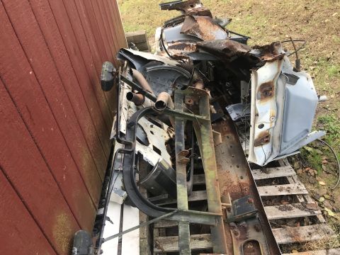 1992 Ford Bronco - A pile of heavily rusted and damaged vehicle parts, including a car door and various metal components, are stacked on wooden pallets next t…