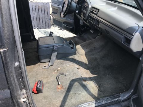 1992 Ford Bronco - The interior of a vehicle, likely a truck or SUV, is shown from the passenger side door opening. The carpeted floor is visible, along with…
