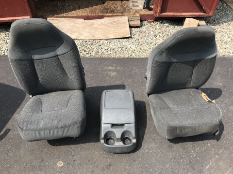 1992 Ford Bronco - Two grey fabric bucket seats and a grey center console with cup holders are laid out on an asphalt surface.