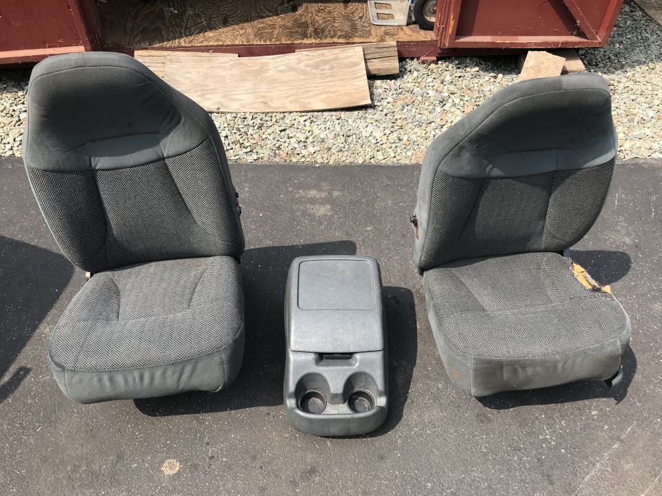 Two grey fabric bucket seats and a grey center console with cup holders.