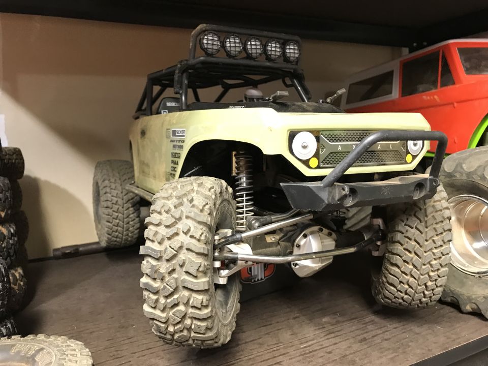 RC rock crawler truck with roll cage, spotlights, and large tires.