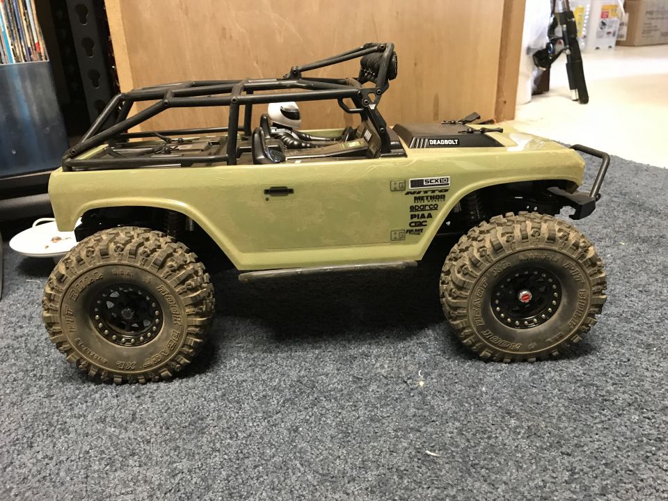 RC rock crawler with roll cage and sponsor decals on carpet.