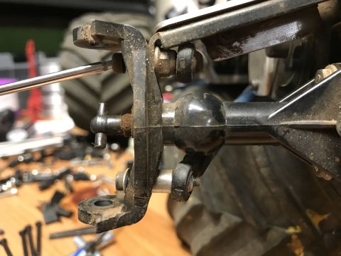 1989 Ford Bronco - A close-up view shows the suspension components of an RC car, including a metal driveshaft connected to a black plastic suspension arm. The…