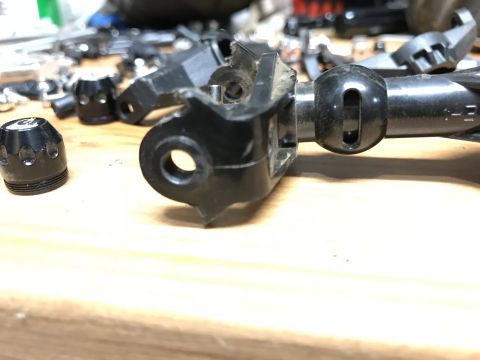 1989 Ford Bronco - A close-up shot of black plastic and metal parts, possibly from a vehicle's drivetrain or suspension, scattered on a wooden surface. One pa…