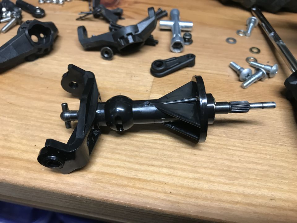 RC car parts disassembled on a wooden surface.