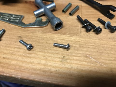 1989 Ford Bronco - A collection of assorted screws, bolts, nuts, and tools are laid out on a wooden surface. The items include a T-handle hex wrench, several…