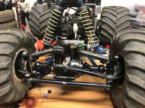 1989 Ford Bronco - Close-up view of the suspension and drivetrain of a remote-controlled monster truck, likely a modified 1989 Ford Bronco. The image focuses…