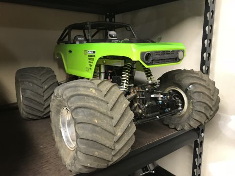 1989 Ford Bronco - A bright green RC monster truck with oversized tires sits on a shelf. The truck features a roll cage, large suspension, and visible brandin…