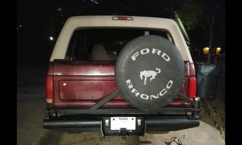 1996 Ford Bronco - Rear view of a maroon Ford Bronco with white top, Ford Bronco logo spare tire cover, tube bumper and Texas license plate, photographed at n…