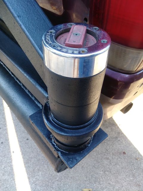 1996 Ford Bronco - A close-up view of a black, textured hub assembly with a chrome ring and a red and silver locking mechanism, mounted on a black metal frame…