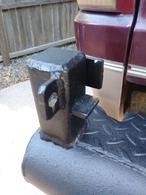 1996 Ford Bronco - A close-up view of a black metal step bumper attachment welded to a vehicle's frame. The attachment has a square post with two brackets and…