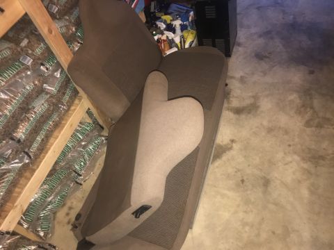 1992 Ford Bronco - Two brown fabric car seats are leaning against a stack of bagged wood pellets. The seats appear to be from a truck or SUV and are positione…