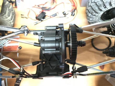 1989 Ford Bronco - A close-up, overhead view of the drivetrain of an RC vehicle, showing the transmission housing and a large spur gear. Wires and suspension…