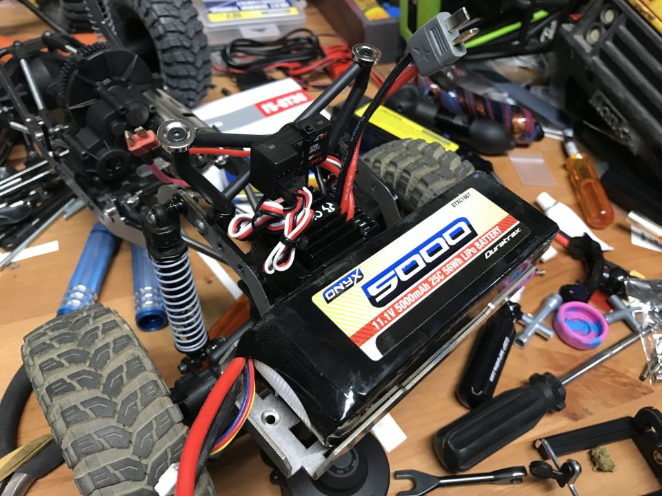 RC car battery pack and electronics on a workbench with tools.