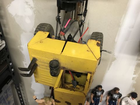 1989 Ford Bronco - A yellow, weathered remote-controlled construction vehicle sits on a wall, with toy wrestling figures visible below.