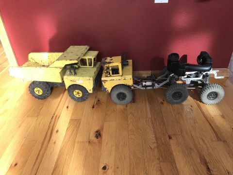 1989 Ford Bronco - A yellow Tonka truck toy is connected to a remote-controlled vehicle chassis with a black body and four large tires. The toys are positione…