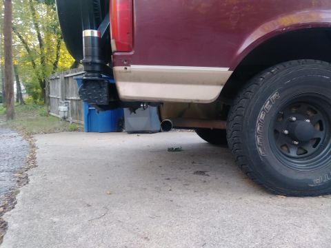 1996 Ford Bronco - The rear passenger side of a maroon and tan Ford Bronco is shown, with a spare tire carrier mounted to the rear bumper. A Cooper tire on a…
