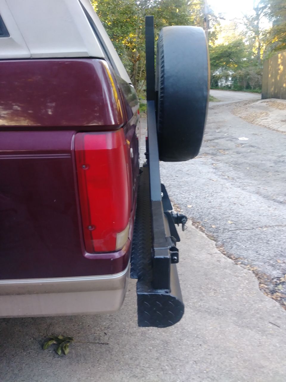 Rear passenger side of a dark red Ford Bronco with a spare tire carrier.