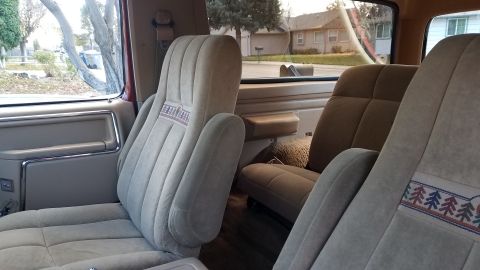 1985 Ford Bronco - Interior view of the front seats of a vintage Ford Bronco, featuring tan velour upholstery with a decorative embroidered trim on the seat b…