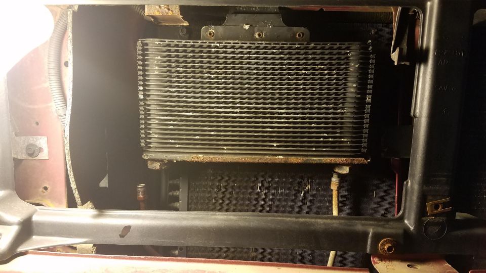 Vehicle transmission cooler mounted above radiator in engine bay.
