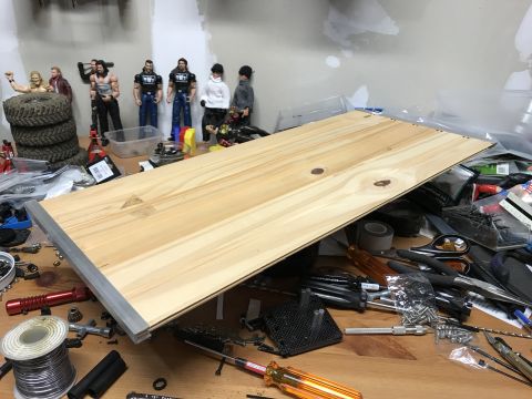 1989 Ford Bronco - A wooden board with metal trim rests on a workbench cluttered with tools and action figures. Tools like screwdrivers, pliers, and a spool o…
